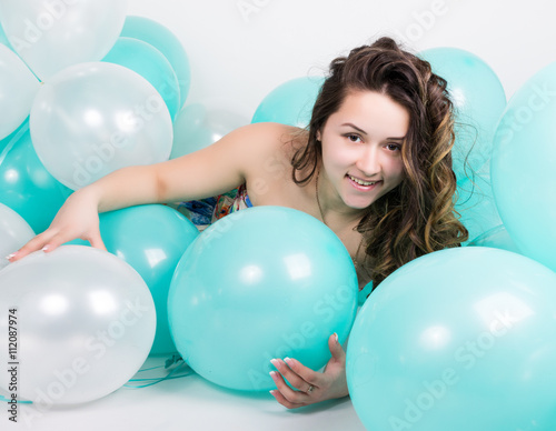 beautiful curly girl in a multi-colored dress playing with balloons