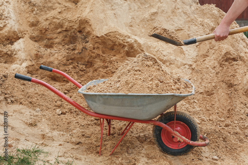 Construction wheelbarrow filled with sand a shovel Fototapet