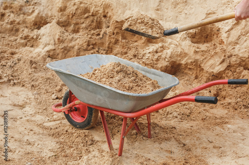 Tableau sur toile Construction wheelbarrow filled with sand a shovel