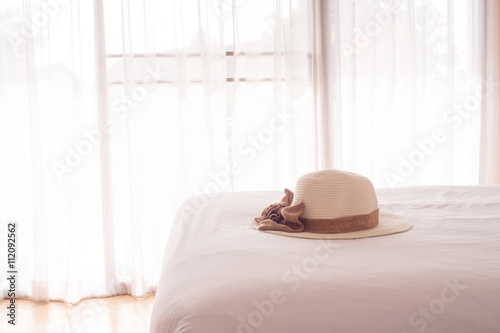 Straw hat on the white bed