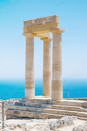 Famous Greek temple three pillars against clear blue sky and sea in Lindos Acropolis Rhodes Athena Temple, Greece