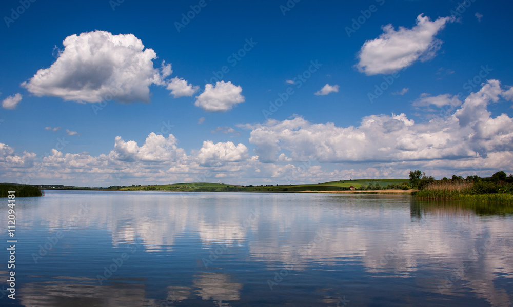Peaceful lake landscape in village on background of blue sky