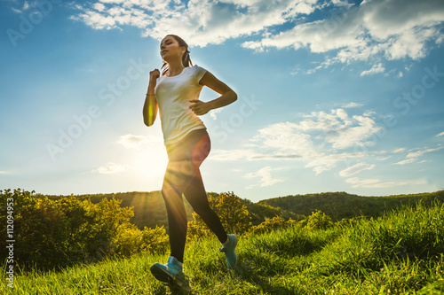 Fototapeta Naklejka Na Ścianę i Meble -  sports girl runs cross-country at sunset in spring