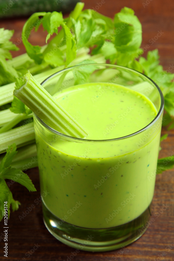 Fresh green celery juice in glass on wooden brown background Fresh green celery juice in glass on wooden brown background