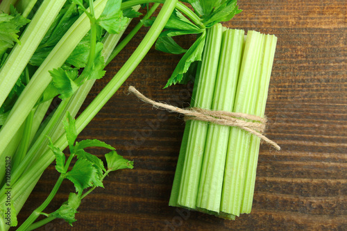 Fresh green celery wrapped with a rope on a brown wooden background