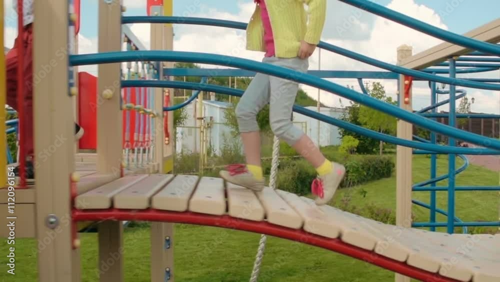 Kids riding down slide on playground and running on green grass in slow motion