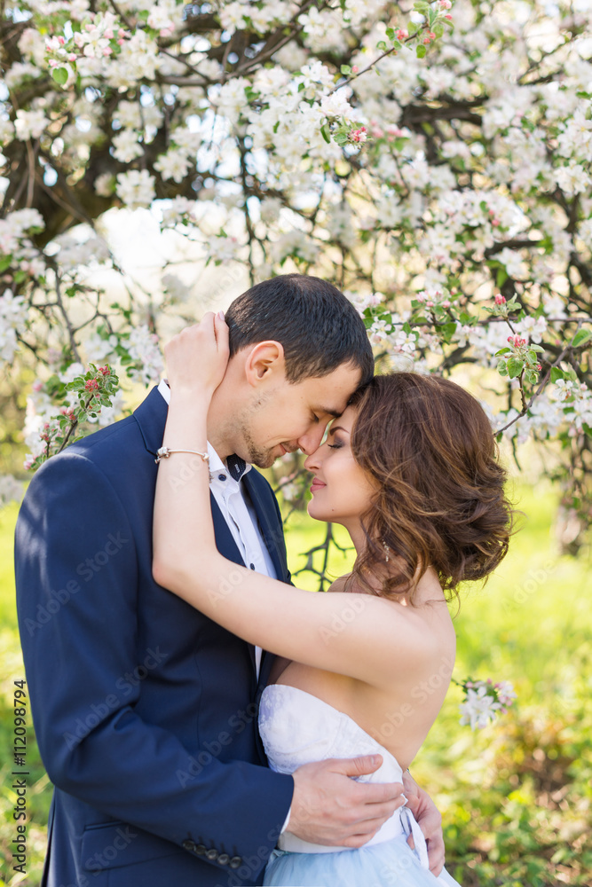 Fototapeta premium Young couple kissing in blooming spring garden. Love and romantic theme.