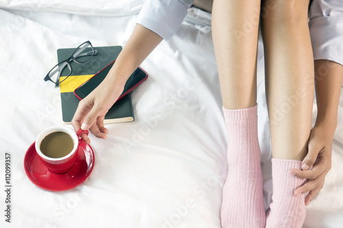 Beautiful woman is drinking coffee on bed, in the morning.