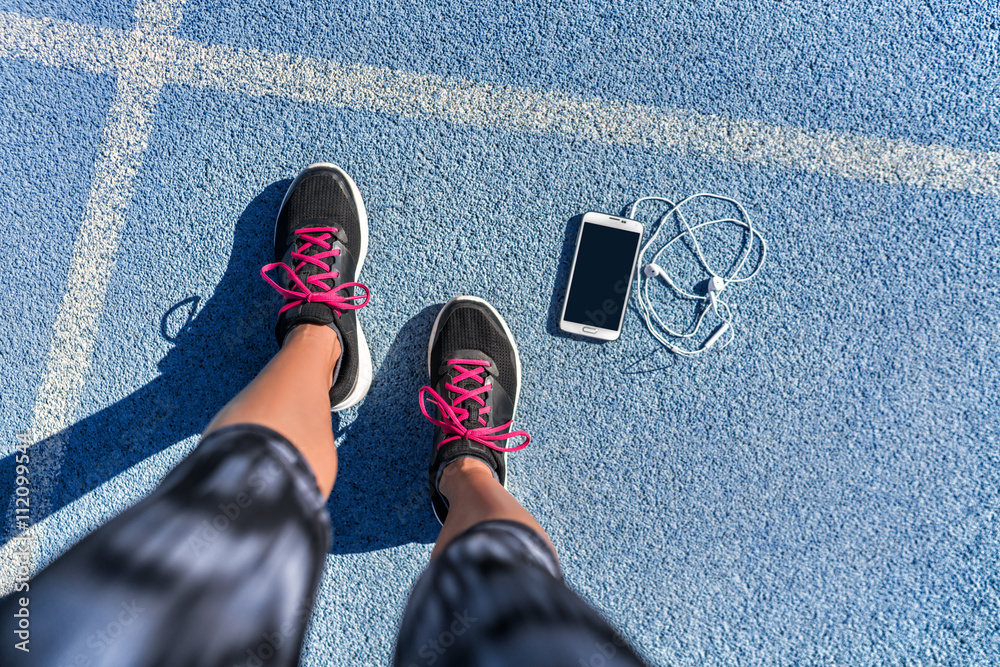 Running shoes girl feet selfie on blue track lane getting ready to run with  smartphone and