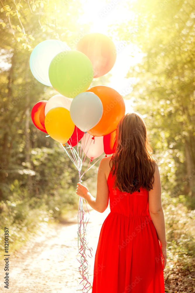 Obraz premium A woman holding a bunch of balloons