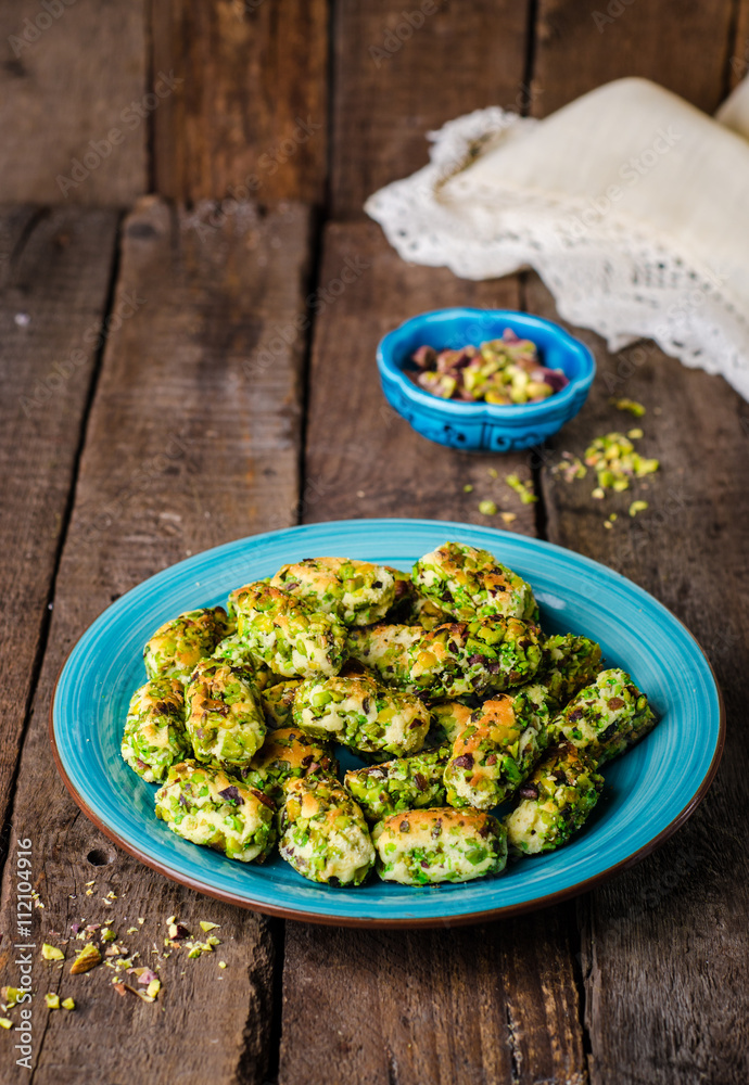 Maamoul - arabic cookies with pistachio in metal bowl on vintage wooden table background. Selective focus Maamoul - arabic cookies with pistachio in metal bowl on vintage wooden table background. Selective focus