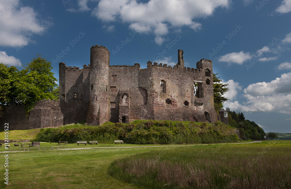 Laugharne Castle, a medieval castle on the river Taf estuary in Carmarthenshire, South Wales, with Dylan Thomas's Boat House tucked away to the right.
