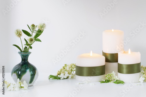 white candles burning with flowers on a white background