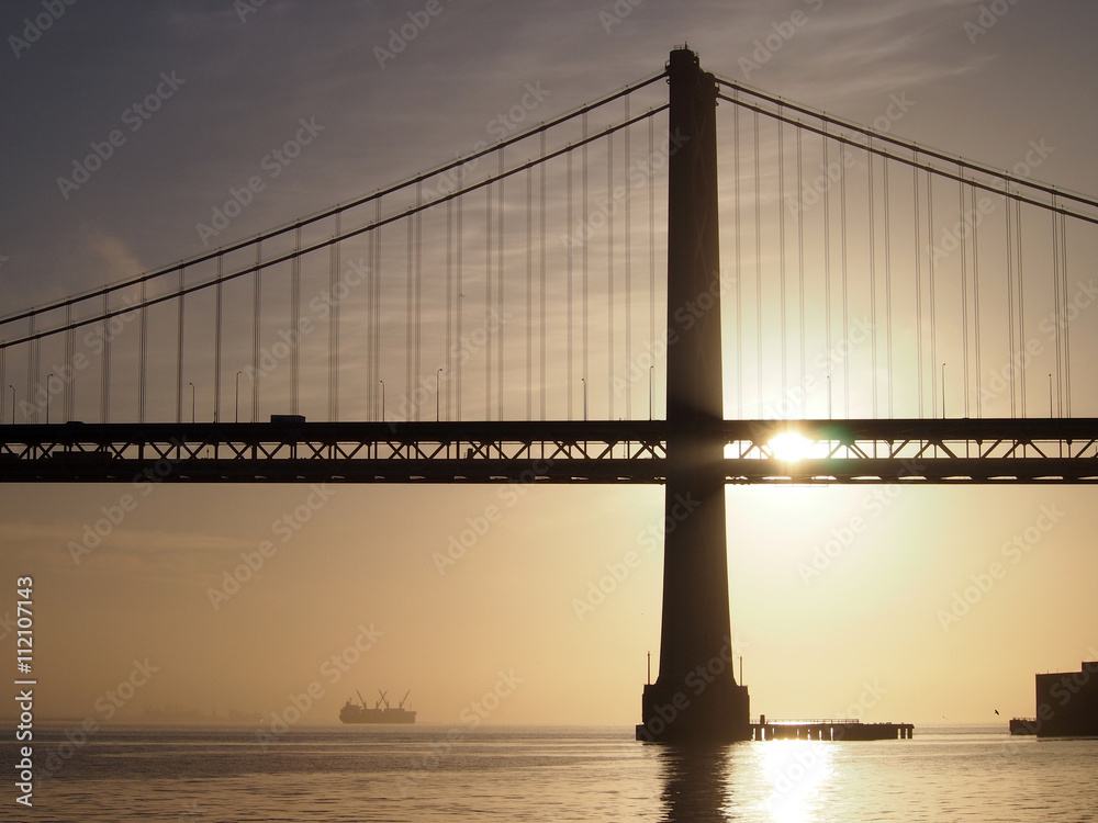 Obraz premium Sunrise over San Francisco Bay and through the Bay Bridge with b