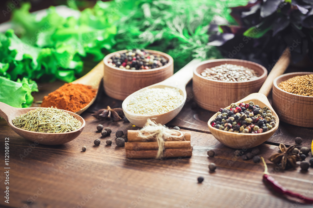 Beautiful colorful spices in wooden spoons and bowls with lettuce, dill and Basil on an old wooden brown table. Free space for your text Beautiful colorful spices in wooden spoons and bowls with lettuce, dill and Basil on an old wooden brown table. Free space for your text