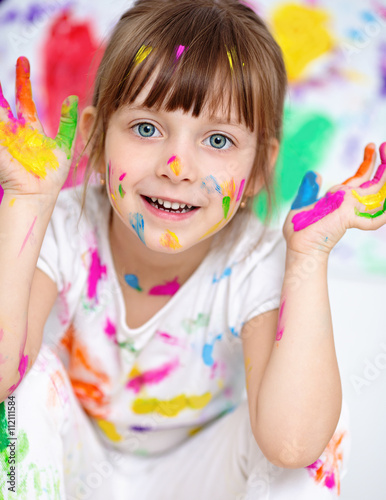Portrait of a cute cheerful happy little girl showing her hands painted in bright colors