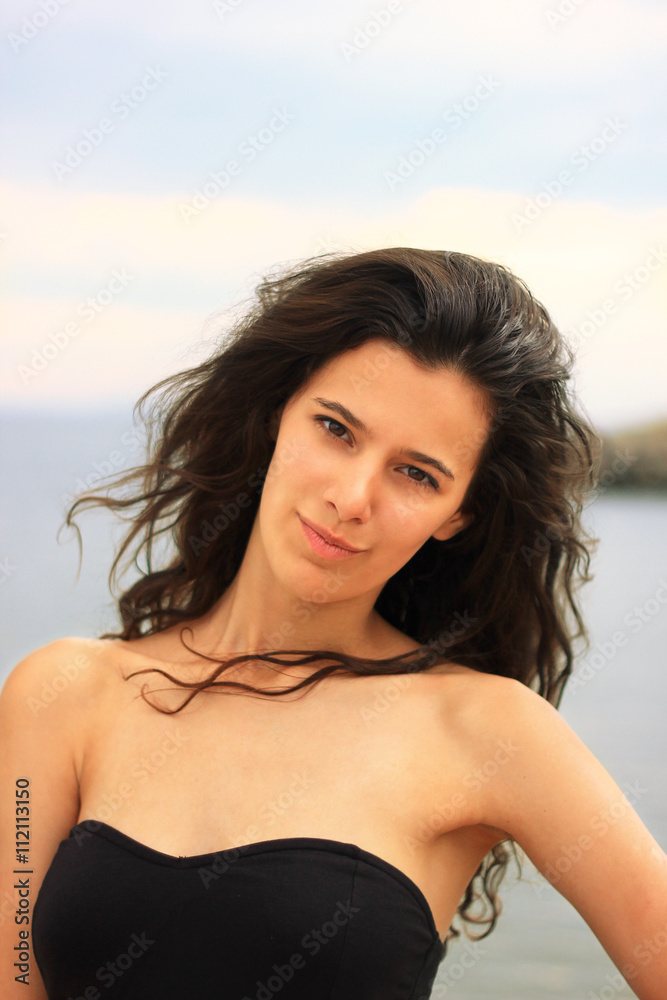 Beautiful slim brunette girl model posing in fashion dress by the sea Beautiful slim brunette girl model posing in fashion dress by the sea