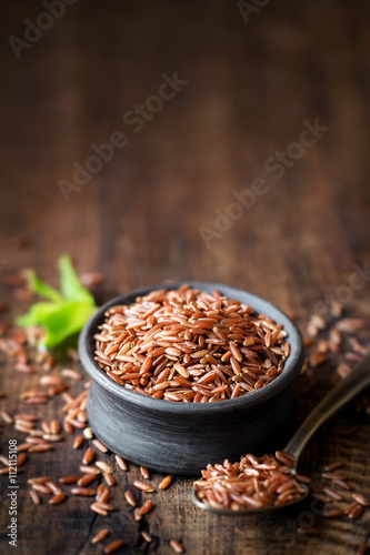 Red rice an a small ceramic bowl against dark rustic wooden background with plenty of copy space for your text