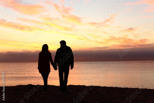Couple silhouettes walking together at sunset
