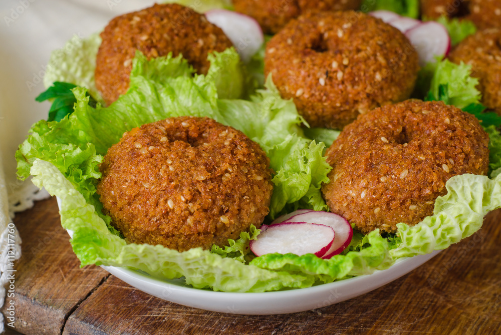 Falafel balls with lettuce on plate on wooden background. Selective focus Falafel balls with lettuce on plate on wooden background. Selective focus