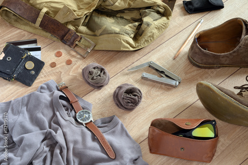 Sand-colored clothes and accessories lie on the wooden floor.