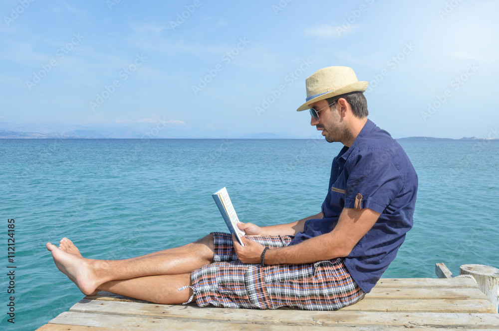 Man sitting on the dock reading a book