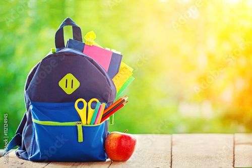 Obraz na plátně Full School backpack with apple on wooden and nature background.