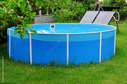 Garden pool with black panels for water heating by the sun