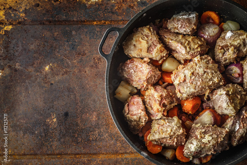 Meat with vegetables in the pan on the metal background