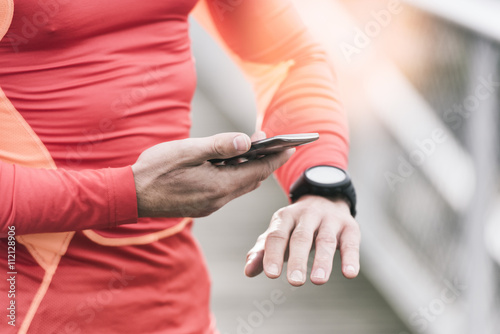 Running man checking sport performance on his mobile phone