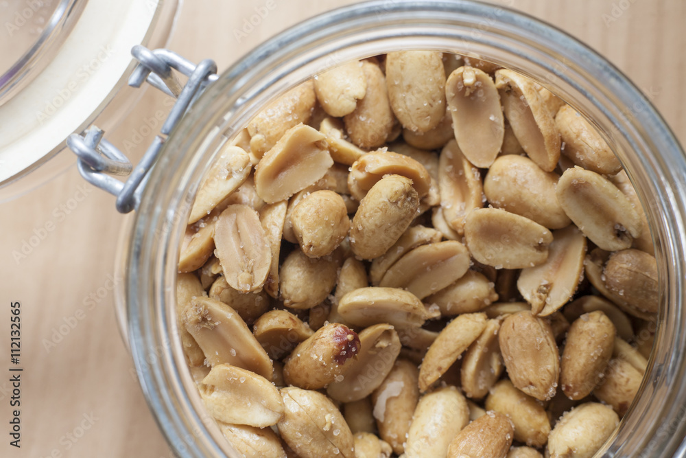 Open canning jar with fried salty peanuts. Overhead view