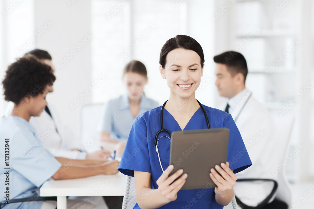 happy doctor with tablet pc over team at clinic happy doctor with tablet pc over team at clinic