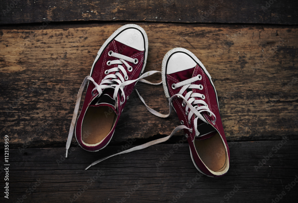 Red footwear of teenage girl on wooden floor. Concept of youth, lifestyle and travel. 