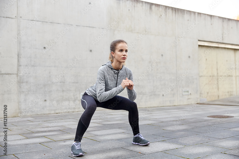 happy woman doing squats and exercising outdoors happy woman doing squats and exercising outdoors