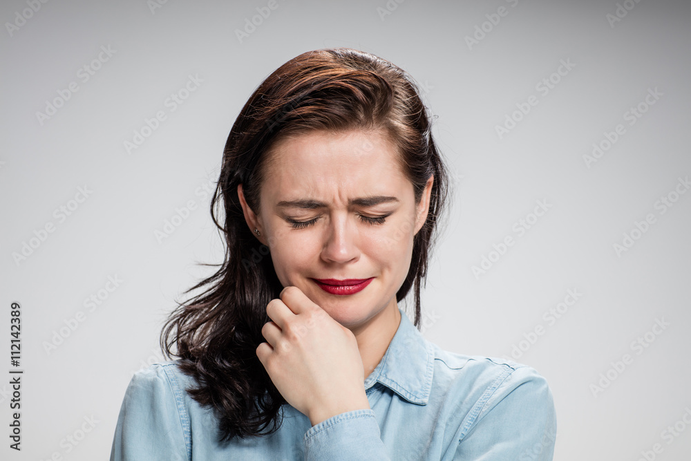 The portrait of a crying young lonely woman on gray The portrait of a crying young lonely woman on gray