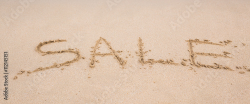 Summer sale handwritten in sand on a beach