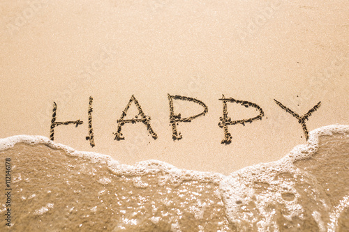 written words Happy on sand of beach