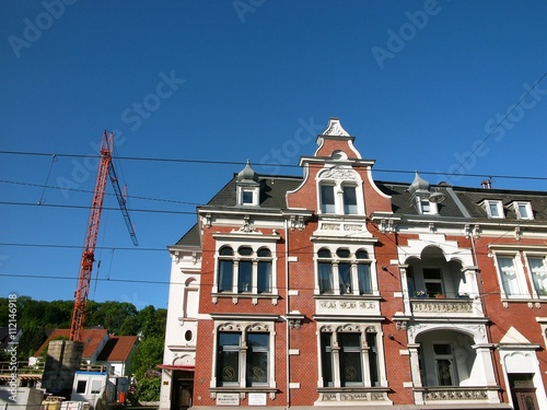 Baukran auf einer Baustelle neben einem wunderschönen sanierten Altbau bei blauem Himmel und Sonnenschein in der Detmolder Straße in Bielefeld im Teutoburger Wald in Ostwestfalen-Lippe photo