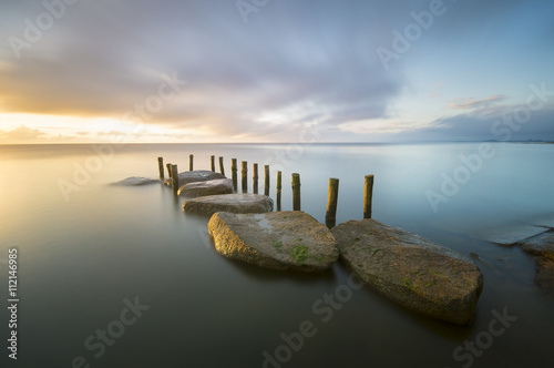 sea landscape, boulders in the water,sunset and colorful sky, slow shutter speed