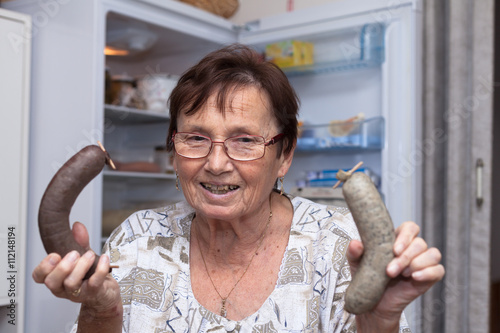 Fotografía Happy senior woman holding pork liver sausages