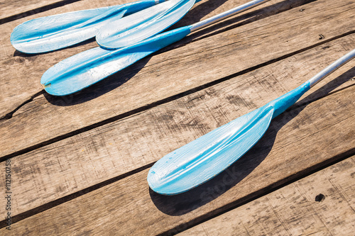 Blue plastic kayak paddle on wooden background