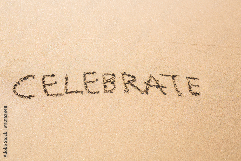 celebrate word handwritten on a sand of beach