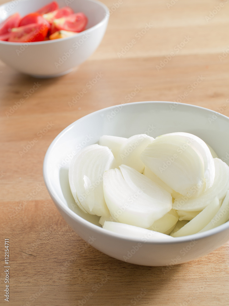 sliced onions in white bowl on wooden table sliced onions in white bowl on wooden table