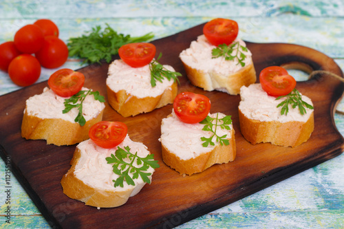 Canapes with cheese  tomatoes and herbs on a wooden background. Sandwiches