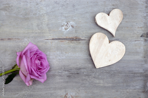 Pink purple rose on a grey old wooden background with white wash heart shape tags with empty copy space 