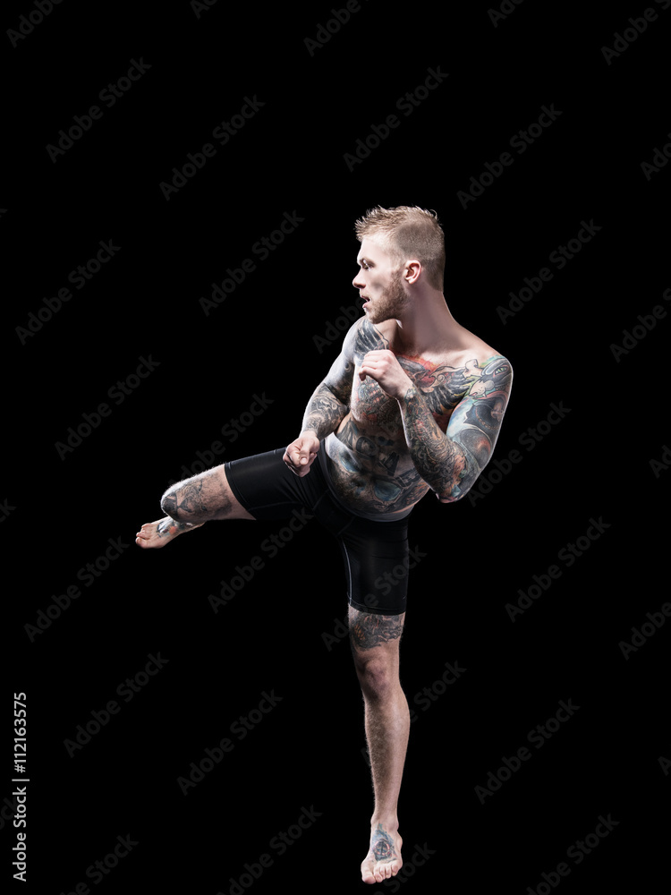 Strong mma fighter prepared high kick on black background
