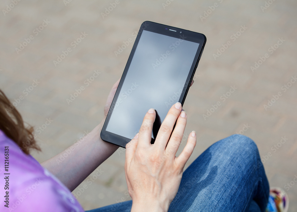 Woman's hands on a screen of a tablet, gray background
