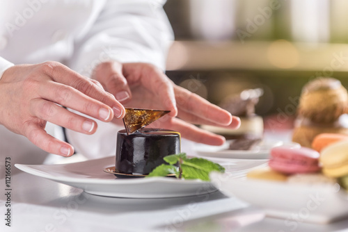 Foto closeup on hands of a pastry chef depositing a chocolate leaf
