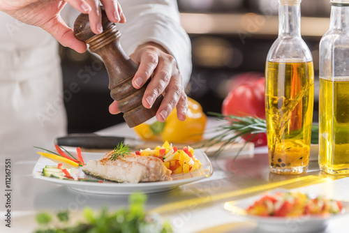 Fototapeta Naklejka Na Ścianę i Meble -   hands of a chef giving a twist of pepper on a cod fillet