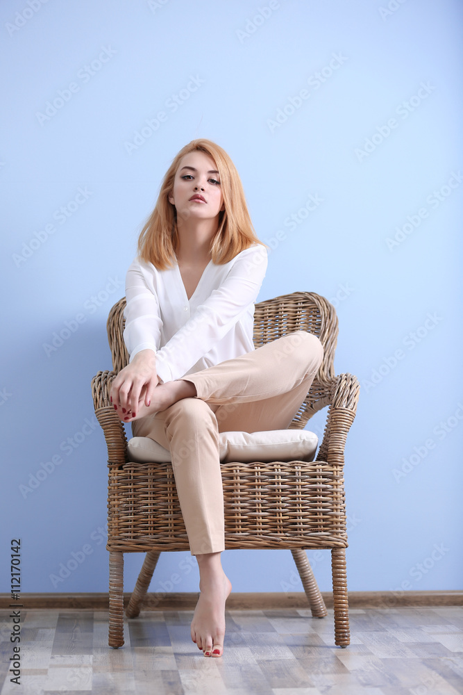Beautiful blonde young woman in white shirt and beige pants on blue wall background Beautiful blonde young woman in white shirt and beige pants on blue wall background